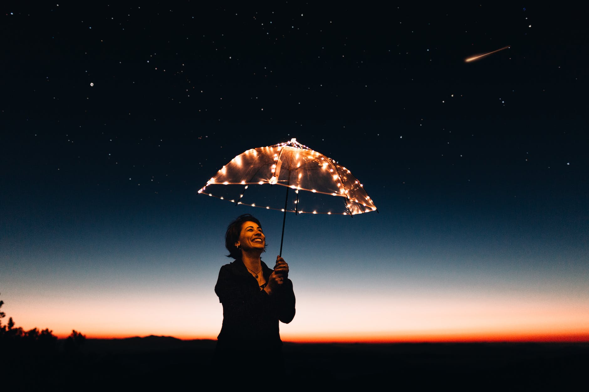 woman using umbrella with lights, symbolizing the journey of leaving the comfort zone.