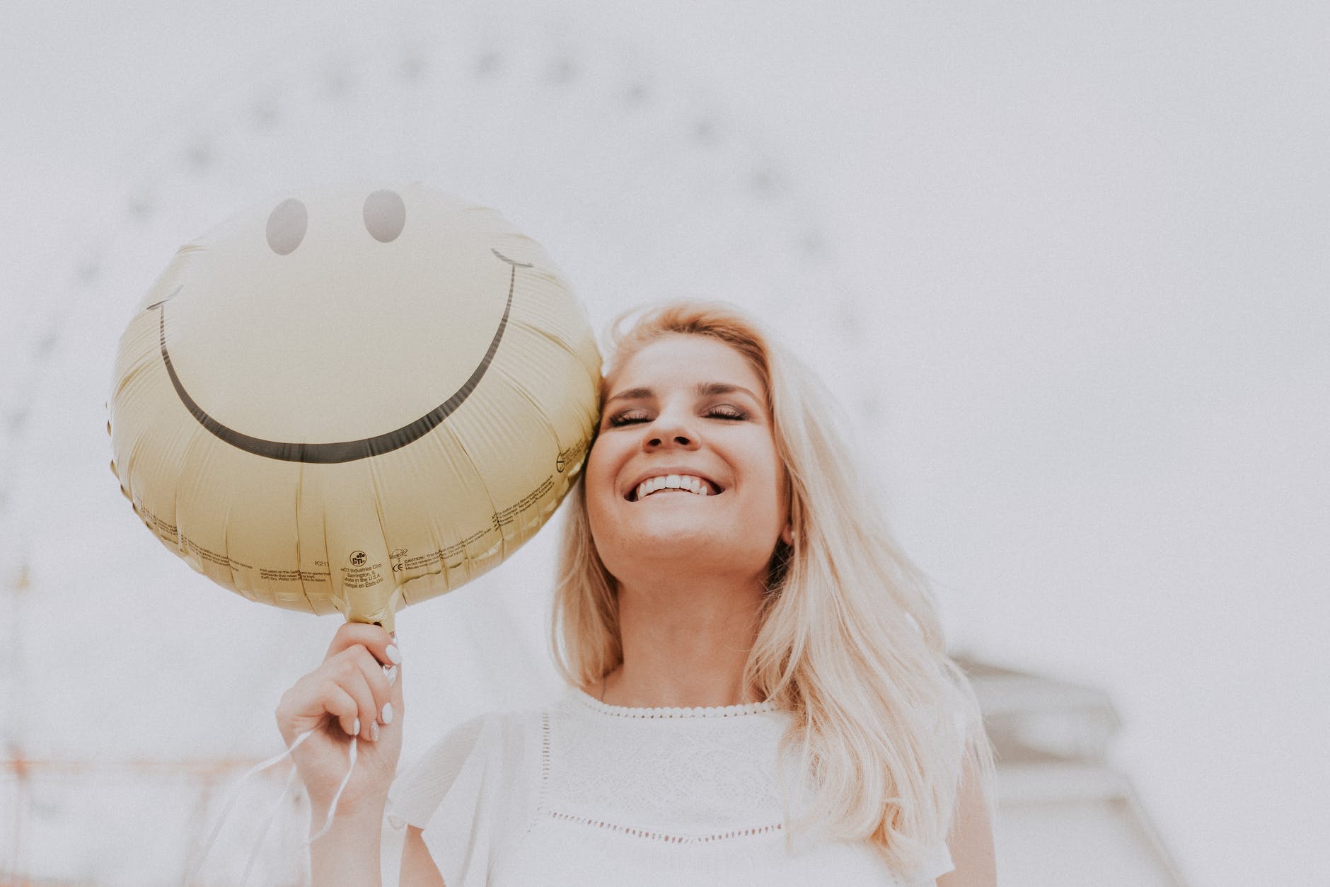 woman holding a smiley balloon and smiling symbolizing the power of positivity