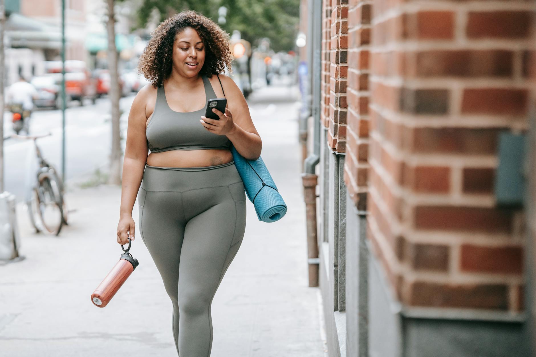 woman walking in sport clothing carrying a yoga mat and achieving health goals