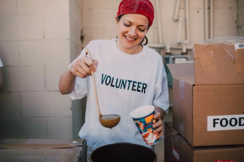 happy woman serving food while volunteering showing the benefits of volunteer work.