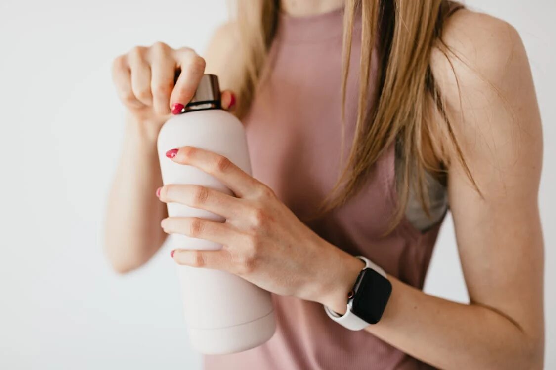 Woman opening a water bottle as part of her morning habit stacking routine for better hydration and health.