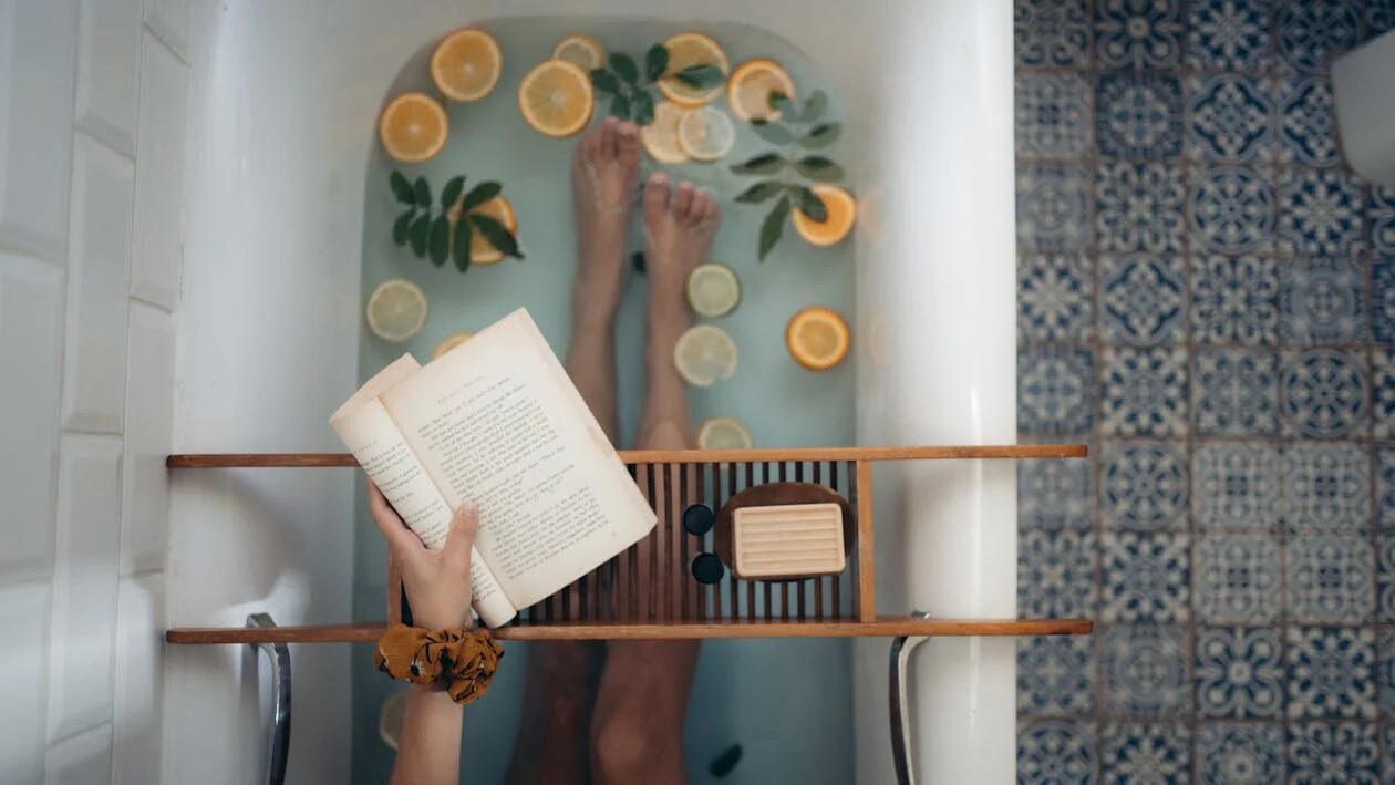 A woman enjoys a serene self-care routine in reading a book while taking a relaxing bath.