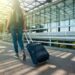 First-time traveler standing with suitcase, at an airport.